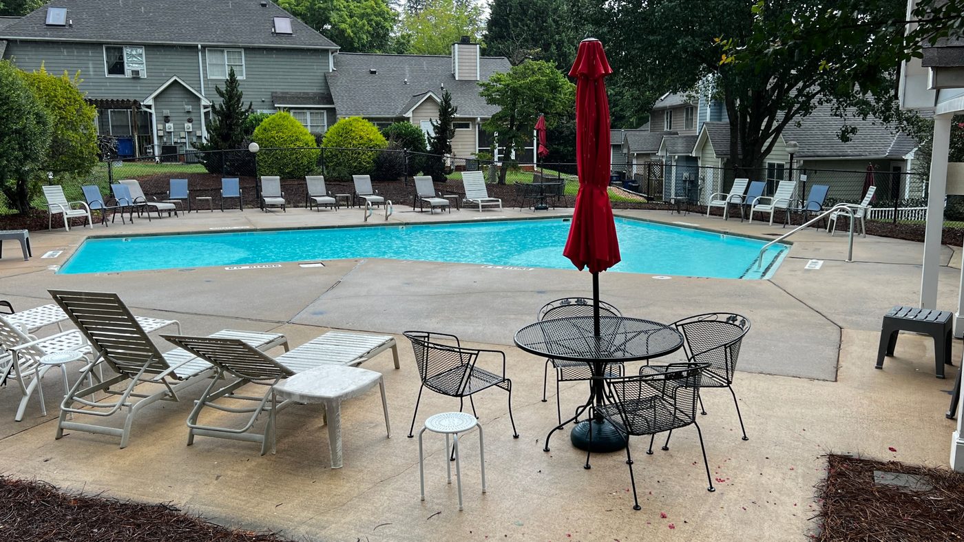 Wynfield community swimming pool with lounge chairs, umbrella tables, and townhomes in the background