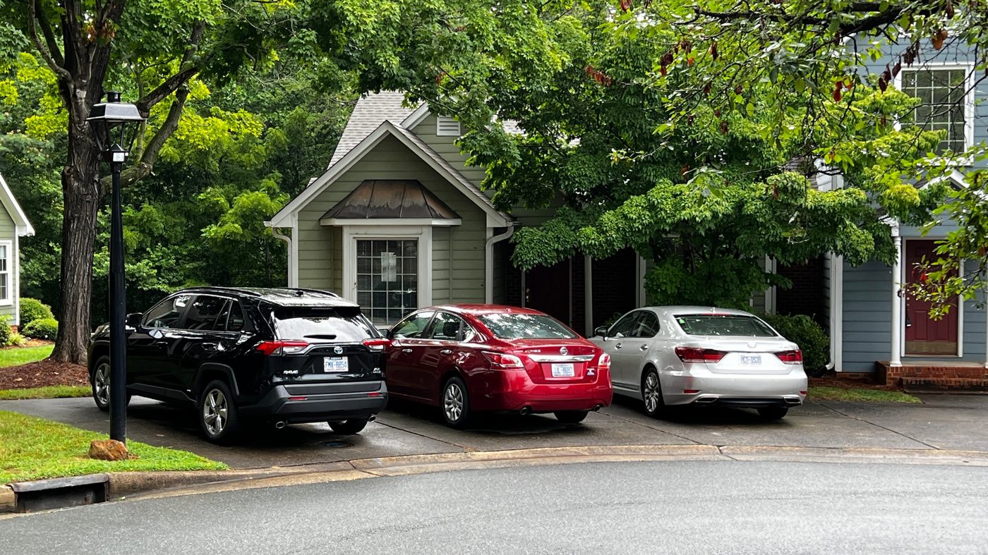 A townhome at Wynfield in Winston-Salem with a sage green exterior, copper awning, and private driveway shaded by mature trees